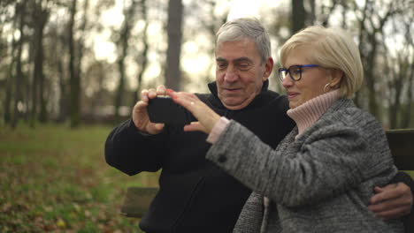 elderly couple taking photos in an autumn park