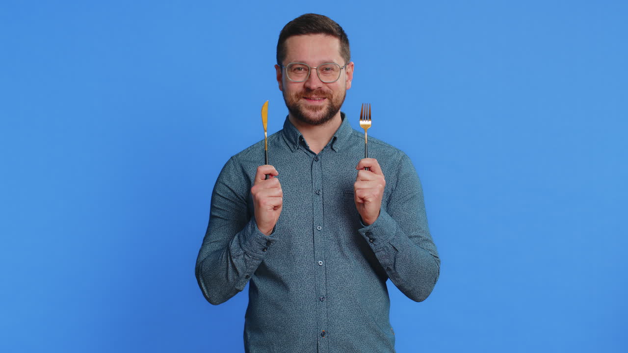 ⁇ 주린 남자가 저녁 식사를 위해 기다리고 있습니다. 불안함으로 식사 접시를 들고 식기 포크 칼을 들고 있습니다.