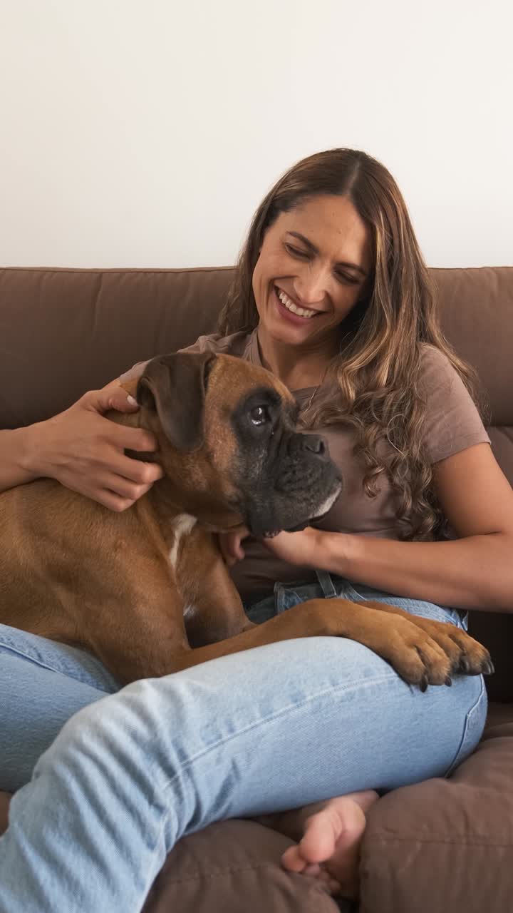 Happy woman with Boxer dog watching TV in modern apartment
