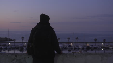 man takes photo of harbor, horizon and docked port boats during sunset dusk