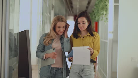 international women's day. business females walking towards the camera in a corridor.