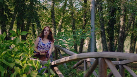 girl crosses a wooden bridge with a basket of wine and grapes long shot