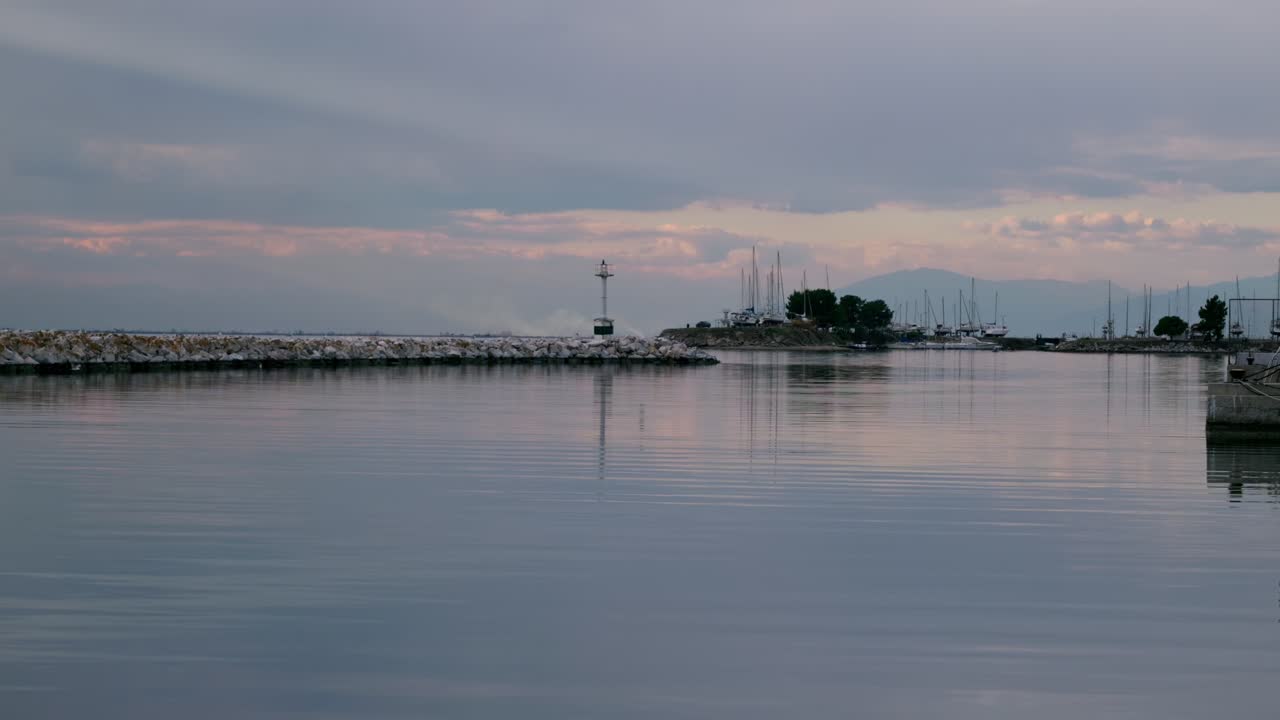 파도와 작은 등대와 함께 구름이 많은 저녁에 작은 항구