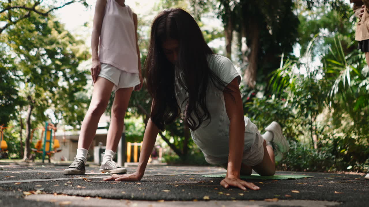 Young Woman Doing Push-Ups on Knees in a Green Park