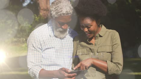 Animation-of-light-spots-over-african-american-couple-using-smartphone