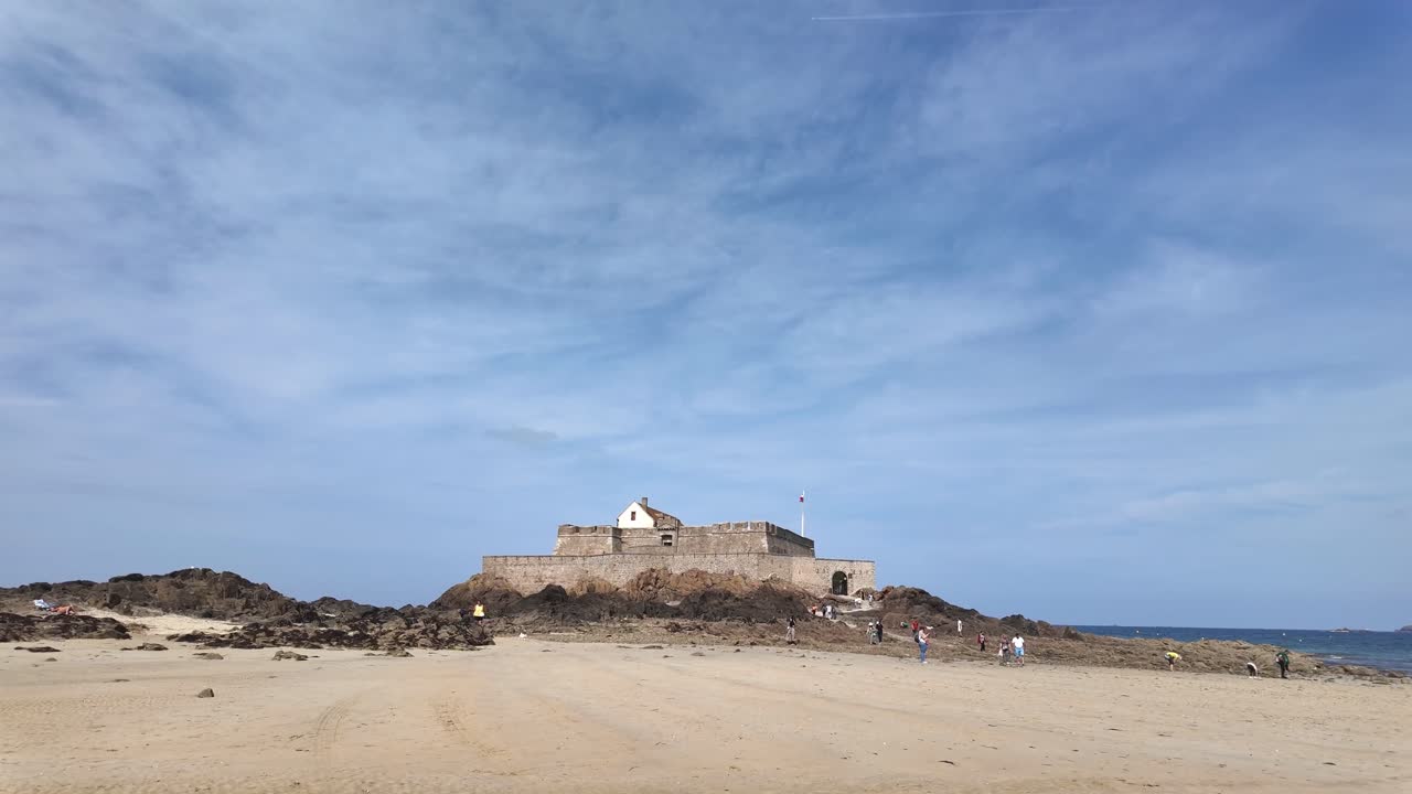Saint Malo, Brittany, sandy beach walking towards Fort National on a sunny day