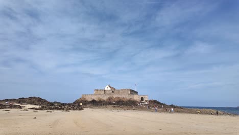 saint malo, brittany, sandy beach walking towards fort national on a sunny day