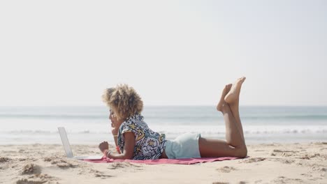 mujer feliz escribiendo en una computadora portátil en una playa