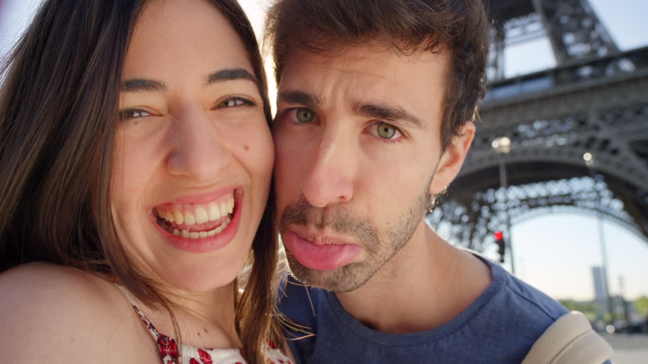 imágenes de video de 4k de una pareja joven tomando selfies frente a la torre eiffel en parís, francia