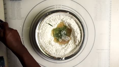 overhead view of hands adding oil with the dry ingredients