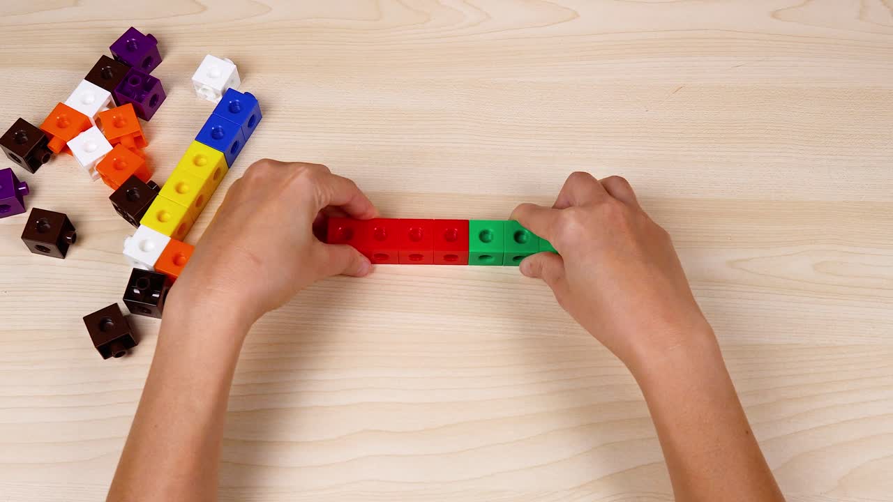 manos montando cubos coloridos en una superficie de madera