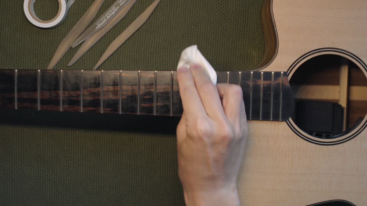 흰색 깨끗한 천을 사용하여 기타 지판에 레몬 오일 클리너 컨디셔너를 적용한 음악가