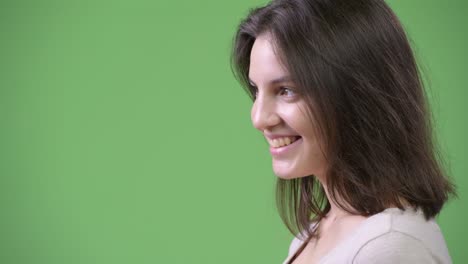 profile view of young happy beautiful woman against green background