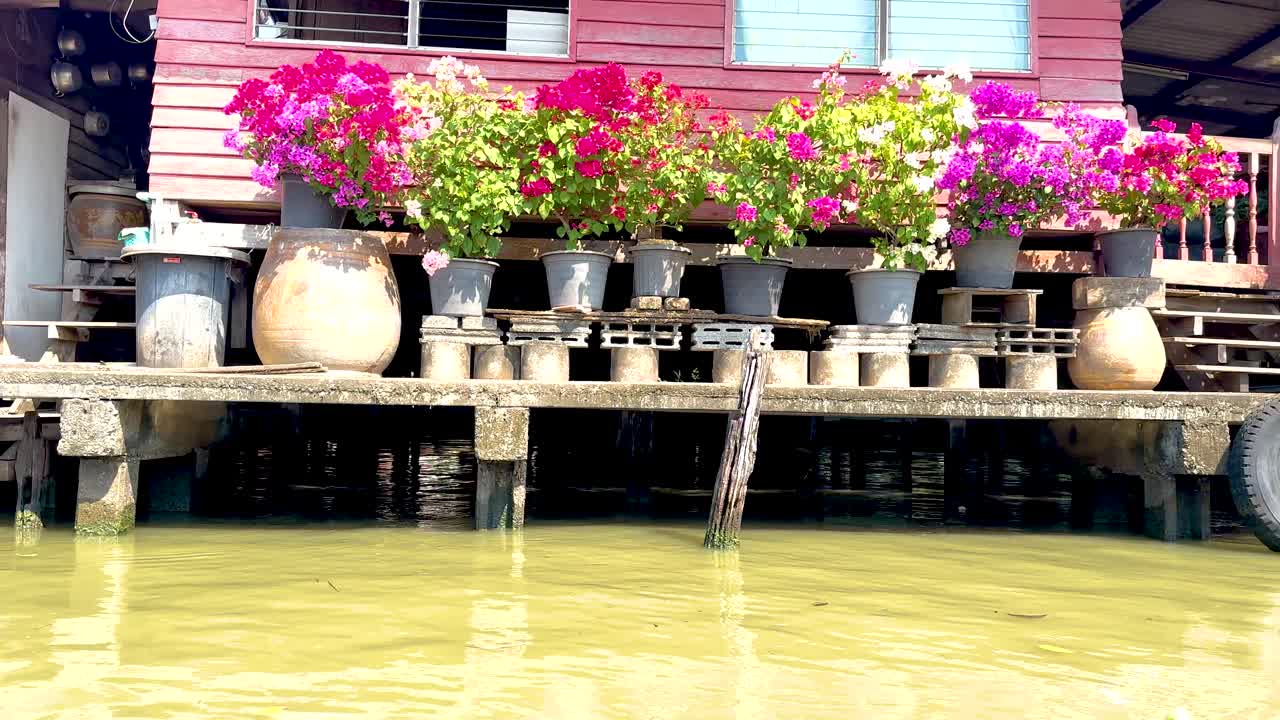 Wooden house with vibrant flowers by canal