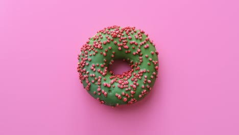 apetitoso rosquilla fresca brillante con glaseado verde girando aislado en rosa. cámara roja dragón 4k