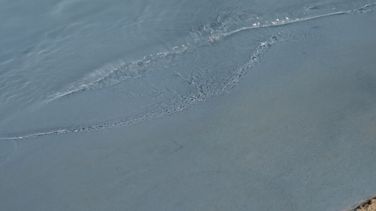 Soft ripples spreading across calm shallow water surface