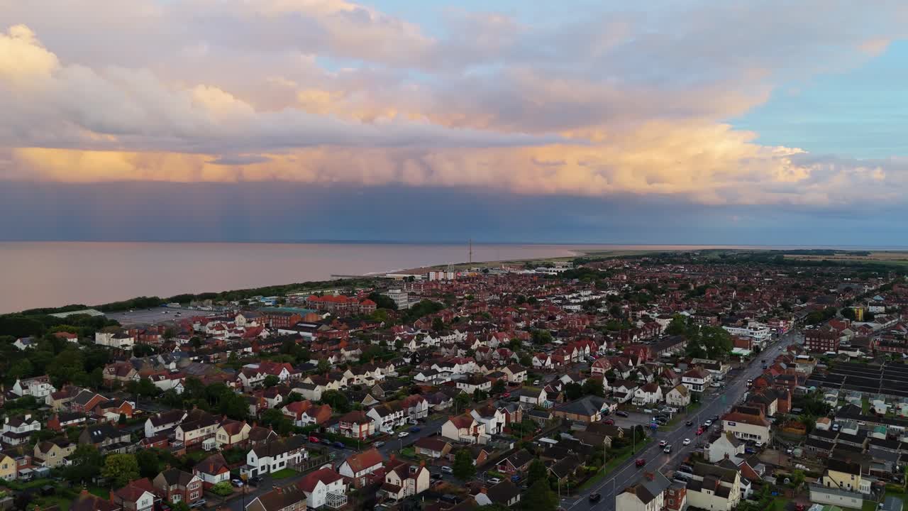Coastal panorama of the town of Skegness with looming storm clouds over the North Sea. Seaside scene with rooftops at sunset