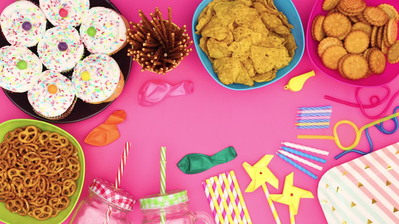 decoraciones de fiestas de cumpleaños, pasteles, comida, globos, pajitas, velas moviéndose sobre un fondo rosa - movimiento de parada