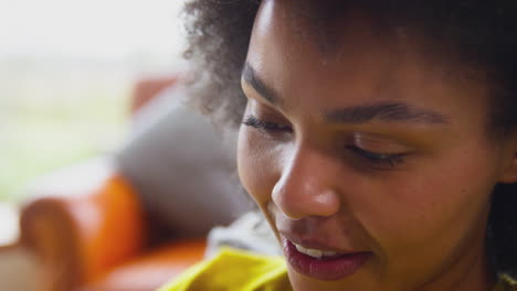 Close-Up-Of-Woman-Relaxing-On-Sofa-At-Home-Using-Digital-Tablet-To-Stream-Movie