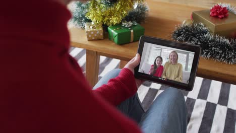 Kaukasischer-Mann-Winkt-Und-Benutzt-Tablet-Für-Weihnachtsvideoanruf-Mit-Lächelnder-Familie-Auf-Dem-Bildschirm