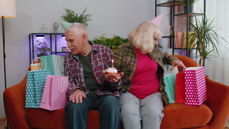 feliz familia anciano hombre mujer celebrando cumpleaños aniversario sostener pastel hace deseo en casa