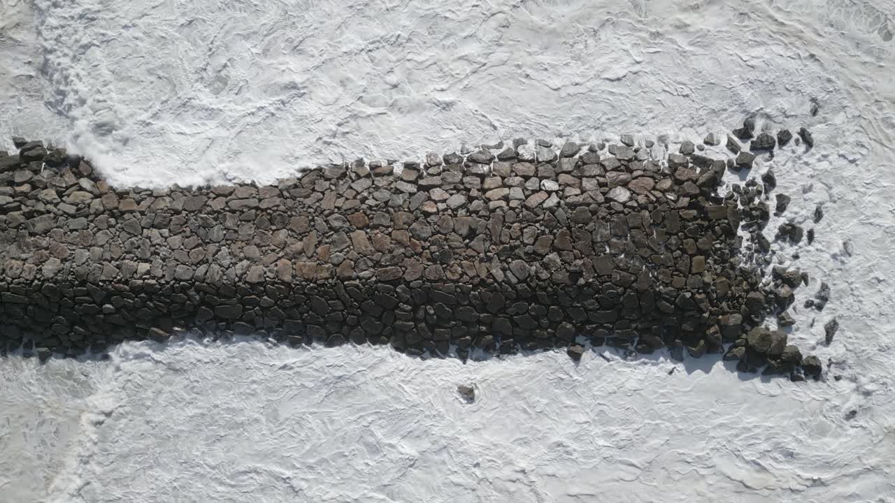 dji mini 3 pro를 사용하여 파도가 부서지고 거품이 형성되는 포르투갈 아베이루의 해상 부두 항공 비디오