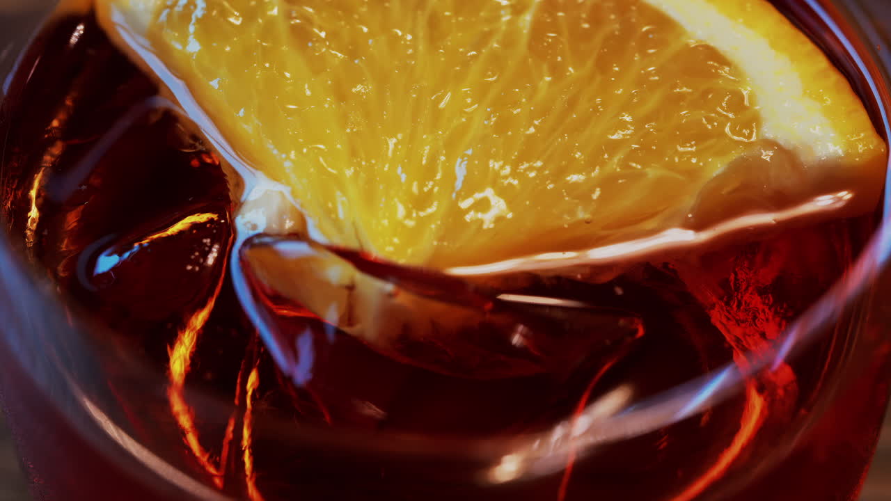 Primo piano di un cocktail Negroni con fetta d'arancia e cubetti di ghiaccio su un tavolo di legno