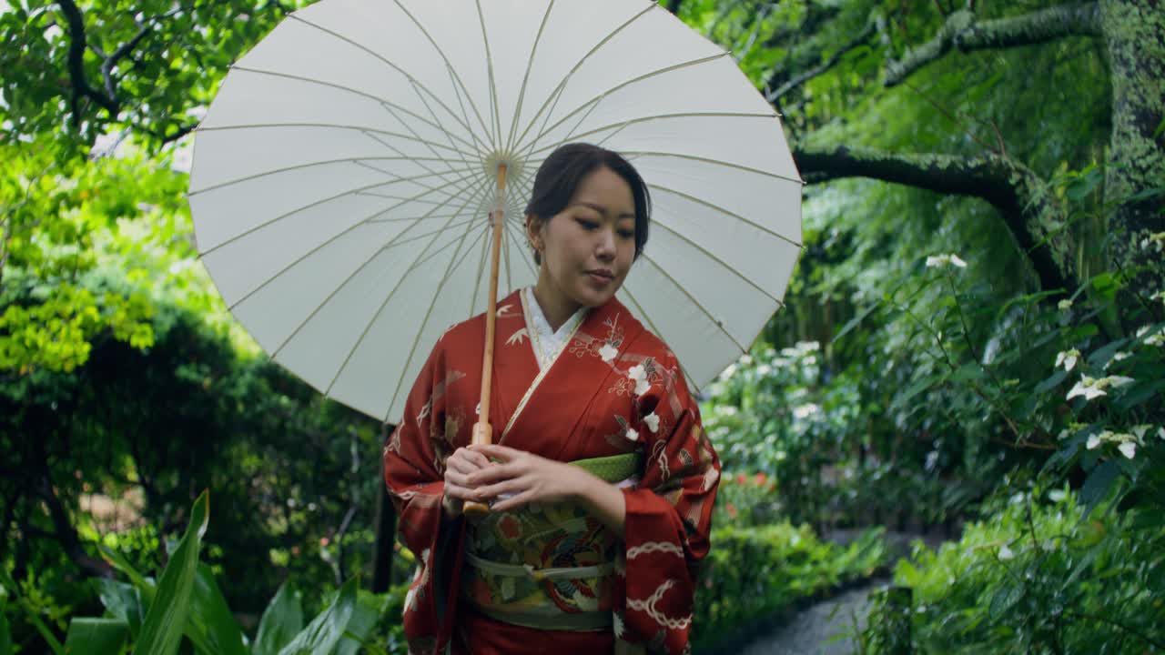 Donna in Kimono con ombrello in un giardino giapponese