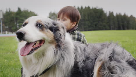 A-carefree-cheerful-kid-peeks-out-from-behind-a-big-shepherd-dog.-Walking-with-a-beloved-friend