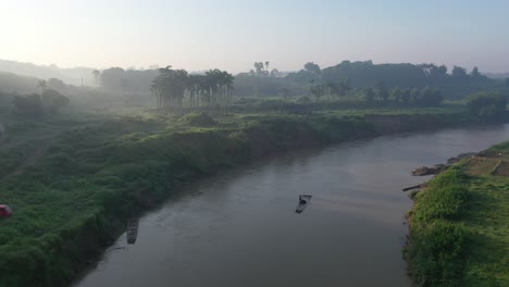 misty river valley landscape with palm trees and rural buildings