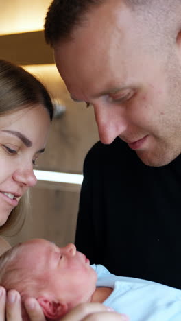 caucasian couple talking and smiling holding their newborn. happy family portrait close up. vertical video