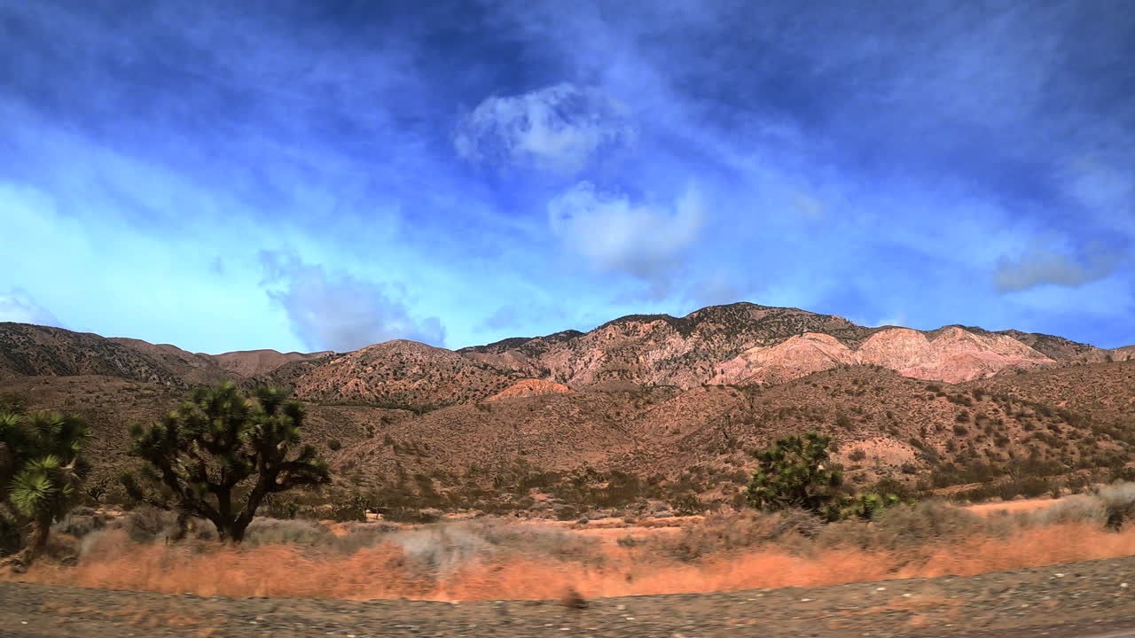 conduciendo a través del paisaje montañoso del desierto de mojave mientras mira por la ventana lateral - punto de vista