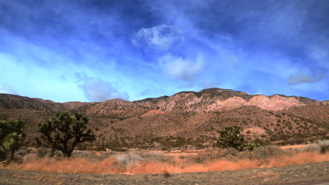 conduciendo a través del paisaje montañoso del desierto de mojave mientras mira por la ventana lateral - punto de vista