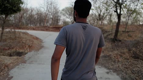 backshot of an athletic young man walking towards the road