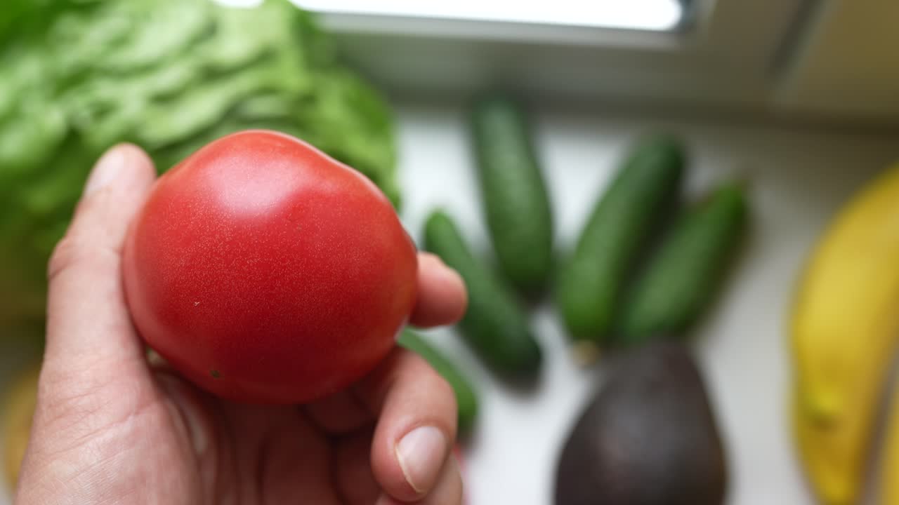 다른 신선한 농산물 과 함께 토마토 를 들고 있는 손