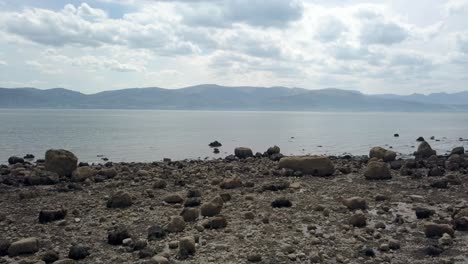 Strange-eerie-Martian-mountain-range-rocky-alien-stone-beach-coastline-slow-forward-to-ocean