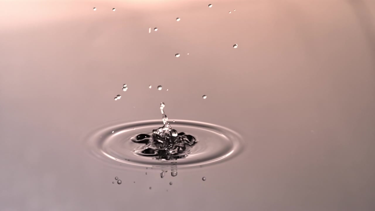 Slow Motion Water Drop Falling and Creating Ripples on a Calm Surface