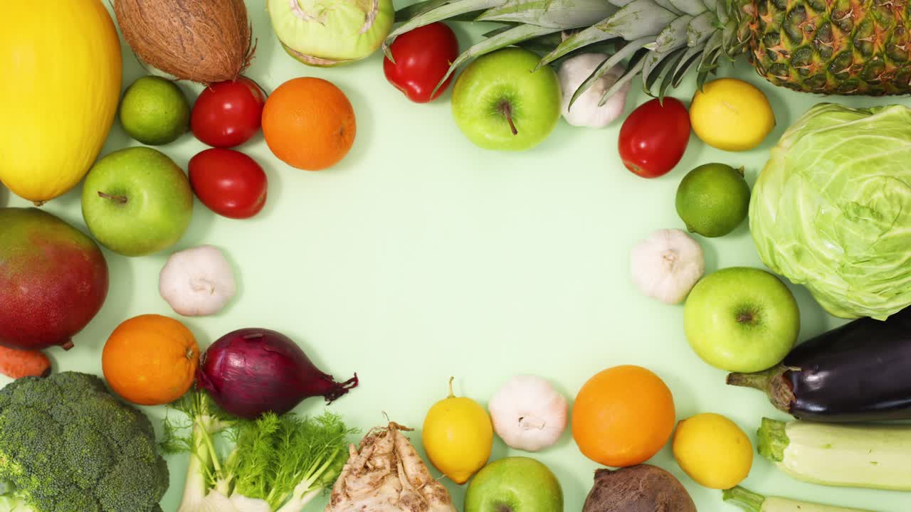 marco saludable hecho de frutas y verduras maduras orgánicas se mueve sobre un fondo verde claro. detener el movimiento