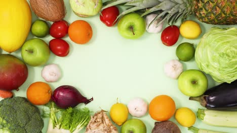 gesunder rahmen aus organischem reifem obst und gemüse bewegt sich auf hellgrünem hintergrund.