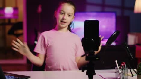 kid filming with smartphone on tripod stabilizer in blue neon lit living room