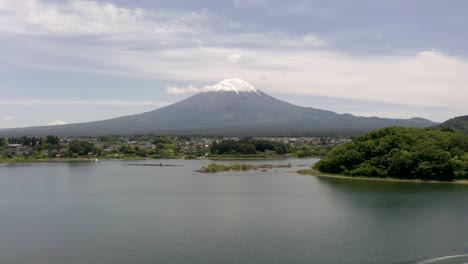 Colorful-aerial-of-iconic-and-majestic-volcano-Mount-Fuji-with-scenic-landscape,-lake-Kawaguchi,-and-snow-capped-peak-on-clear-sunny-day-in-Fuji,-Japan