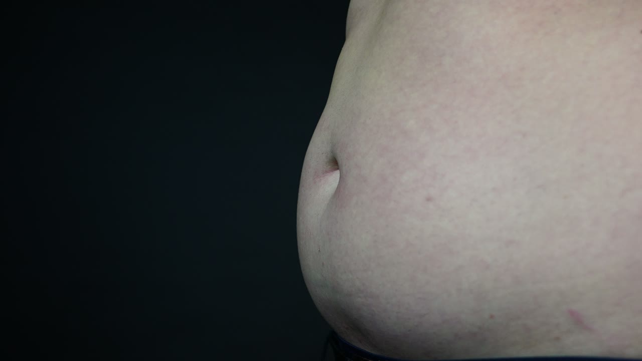 Uomo in sovrappeso che si schiaffeggia la pancia, vista laterale, slow motion