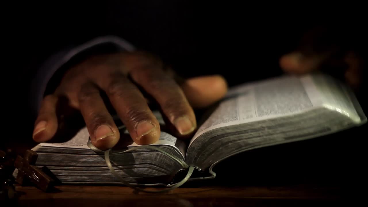 성경과 함께 손으로 신에게 기도하는 남자 검은 배경으로 기도하는 캐리비안 남자 스톡 비디오