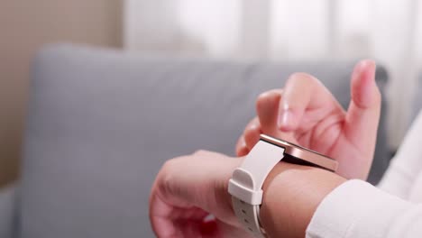 cierre de las manos de la mujer usando un reloj inteligente y configurando la aplicación en la sala de estar