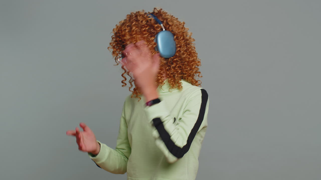 Happy teenager child girl kid listening music on headphones dancing disco fooling around relaxing
