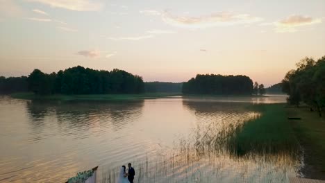 aerial view of a couple getting married near a lake during the sunset