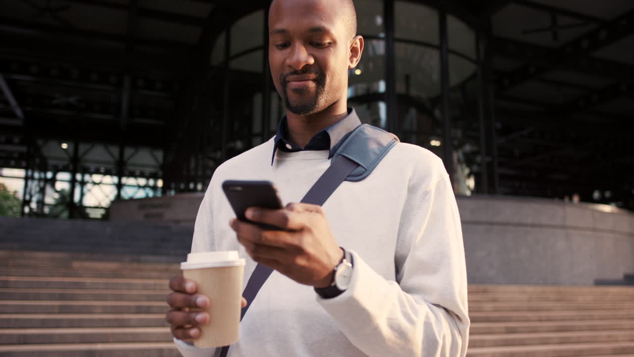 Businessman using smartphone outdoors, taking a coffee break