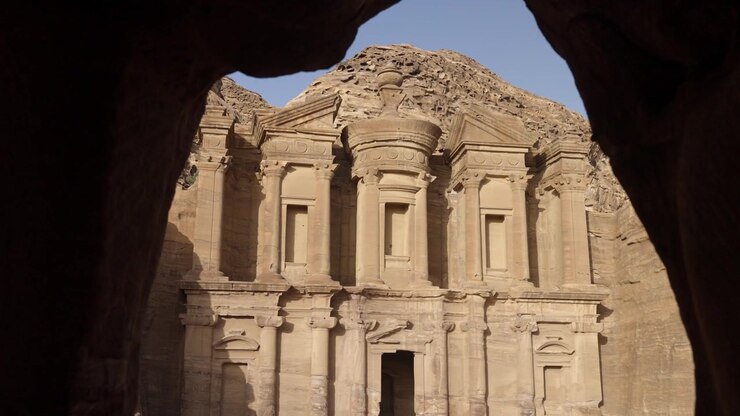 Ad Deir (Monastero) soleggiato nel deserto di Petra in Giordania, visto da una nicchia rupestre
