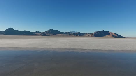 una toma aérea de drones revela agua tranquila que cubre la sal blanca de las salinas de bonneville y las montañas distantes