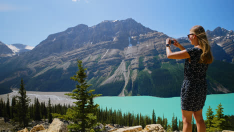 mujer haciendo clic en fotos con el teléfono móvil mientras está de pie en una roca 4k